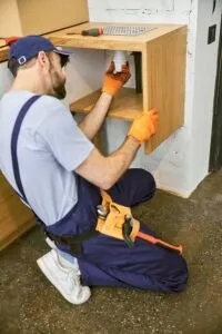 Plumber repairing pipework under a kitchen sink